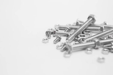 Beyaz arkaplanda birçok somun ve cıvatanın seçici odağı