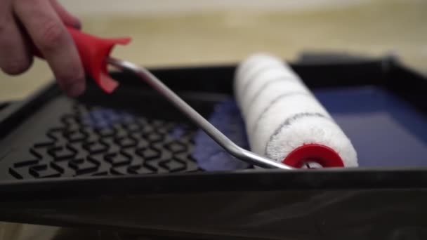 The worker runs roller on tray with paint. white roller with red handle is dipped in blue paint. — Stock Footage The worker runs roller on tray with paint. white roller with red handle is dipped in blue paint. Royalty Free Stock Video