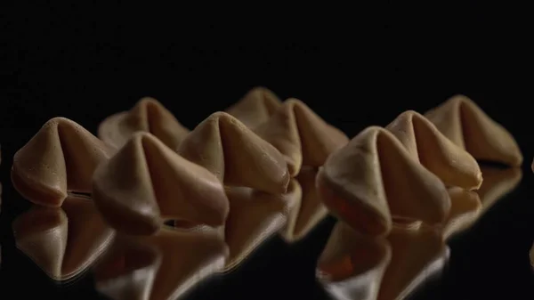 Low key light. A lot of Chinese cookies rotate on a black background. Traditional fortune cookie. Nice view on spinning biscuit crispy sweet cookie.