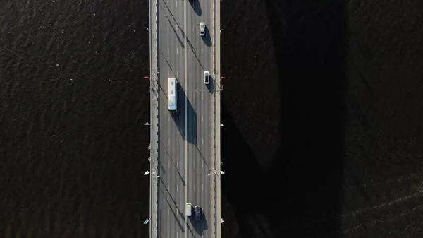 Straight down drone footage of bridge in middle of canal or lake separating sea from sweet water. Commuter or tourist traffic vehicles and cars drive by
