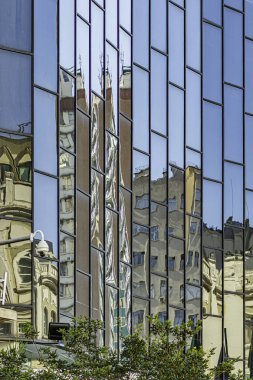 Şehir manzarasının çarpık yansımalarını yansıtan bir bina.