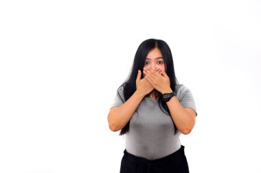 İki elini de kullanarak ağzını kapatan Asyalı güzel bir kız ayakta duruyor. izole edilmiş beyaz arkaplan