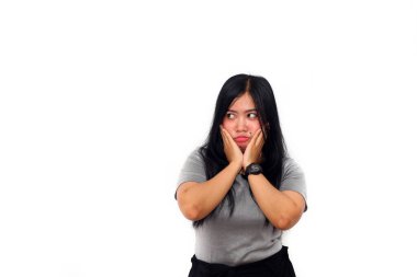 Güzel Asyalı kız yan yan bakarken üzgün bir ifadeyle ayağa kalktı. İki elini de yanaklarından tut. izole edilmiş beyaz arkaplan