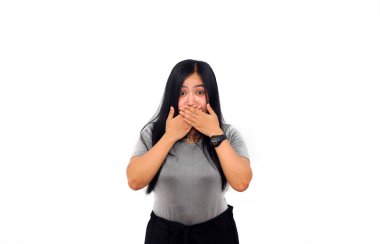 İki elini de kullanarak ağzını kapatan Asyalı güzel bir kız ayakta duruyor. izole edilmiş beyaz arkaplan