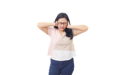 Güzel stresli Asyalı kız kulaklarını kapatırken ayağa kalktı. Beyaz arkaplanda izole