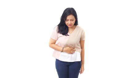 Güzel Asyalı kız karnını tutarken ayakta duruyor. Sağlık hizmeti konsepti. Kopyalama alanı ile beyaz arkaplanda izole