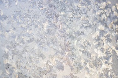 Pencere camında buz desenleri var, içinden ışık görünüyor. Yatay pankart. Seçici odaklanma. Kış, soğuk, Noel zamanı hakkında yaratıcı bir geçmiş.