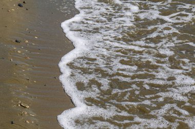 Deniz kıyısı dokusu. Temiz kum üzerinde çizgi halinde su köpüğü. Hirozontal