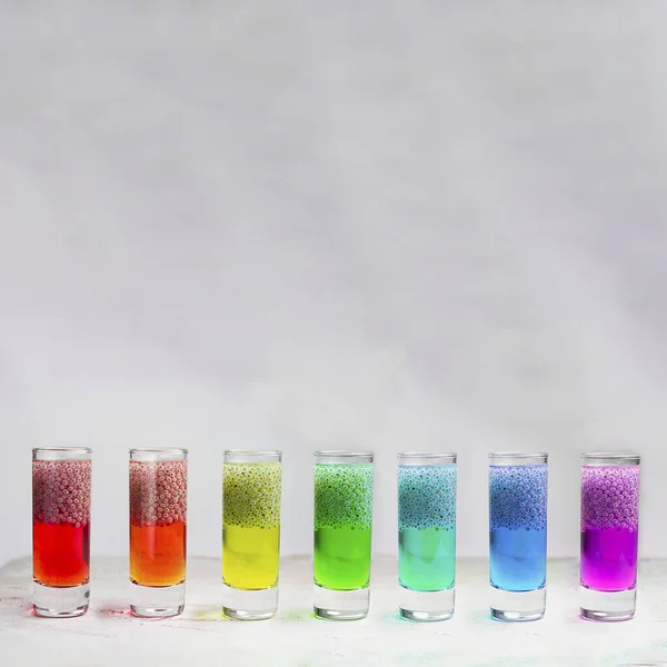 Seven Rainbow Shots with basil seeds brights drinks, on the grey textured background. Square with copy space for text and design. Minimal cpncept about healthy beverage. — Stock Photo, Image