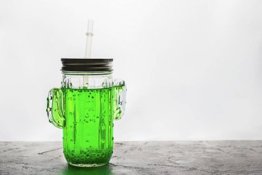 Smoothie modayı takip eden kaktüs şekilli yeşil fesleğen tohumlu kavanoz. Arka planda gri renkli saman var. Yatay, kopyalama uzayı. Sağlıklı içecekler ve süper yiyecekler hakkında minimum konsept. Falooda, sabja