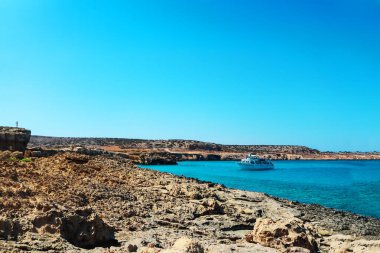 Limanda küçük beyaz bir gemi. Gündüz teknenin hava görüntüsü. Tekne, kaya, deniz, mavi gökyüzü manzarası. Avrupa 'da yüzen tekne. Seyahat et. Tatil köyü. Kıbrıs
