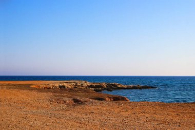 Issız deniz kıyıları, kızıl kıyıları, kayaları, denizi ve mavi gökyüzü olan manzaralar. Seyahat et. Turistler için popüler olmayan bir yer. Kıbrıs