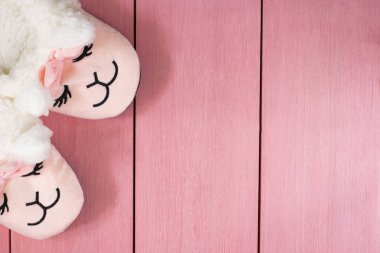 Uyuyan sevimli pembe lamalı terlikler giyen kadın. Yumuşak pastel renkler. Ahşap arka planda pembe.
