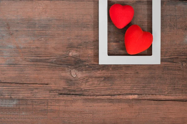 Par de corações vermelhos em moldura branca na mesa de madeira vintage, vista superior. Dia de São Valentim fundo — Fotografia de Stock