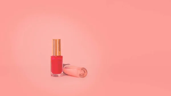 Two glass bottles with nail polish. Isolated object on coral background. Tone. Nail polish. Beauty. Manicure. Colour. Coral. Copy space. Horizontal — Stock Photo, Image
