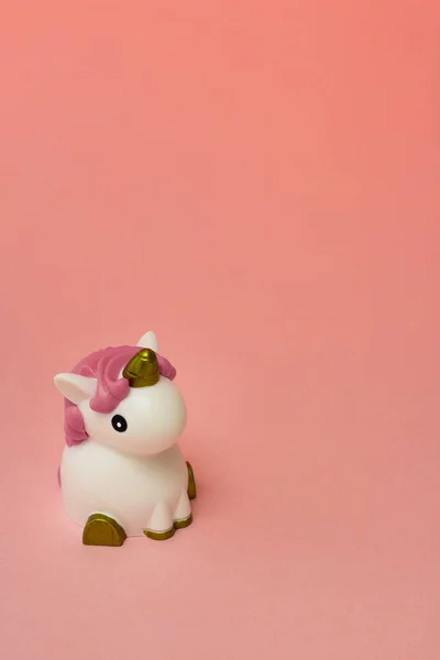 Невелика мила біла іграшка єдинорога з рожевим гребенем на кораловому порожньому тлі. Ізольовані. Копіювати простір. Символ. Крихітко. Колір. Вертикальний — стокове фото