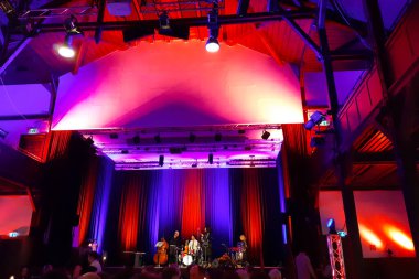 Almanya 'nın Riss şehrinde, Biberach, Gigelberghalle' de akşam yemeği. Şubat 2019. Mor, menekşe ve kırmızı ışıklarla güzel bir konser salonu, metal kostümleri ve sahne editörleri var.