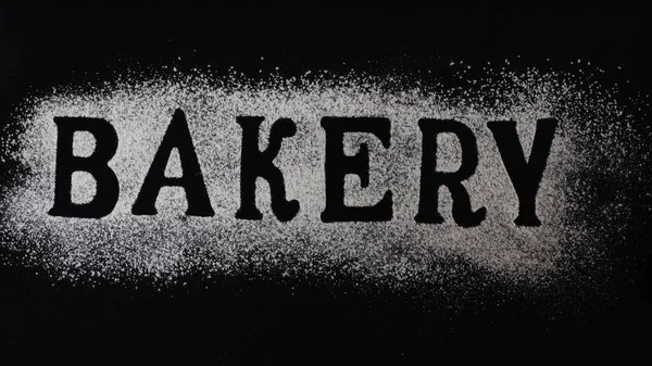 Letters of word bakery made with sieved flour on black table background, Preparation for baking, horizontal banner, Lettering — Stock Photo, Image