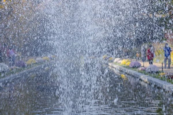 Spritzwasser des Brunnens auf dem Hintergrund des Teiches und defokussierte Menschen, die aufwachen, Herbst, Stadtpark, horizontal mit Kopierraum, — Stockfoto