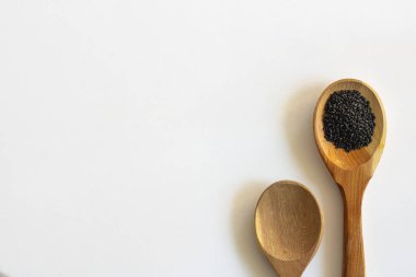Tahta kaşıkta tatlı fesleğen tohumları ve beyaz arka planda boş bir tane. İzole et. Süper yiyecek ve sağlık hakkında metin ve tasarım için kopyalama alanı ile yatay