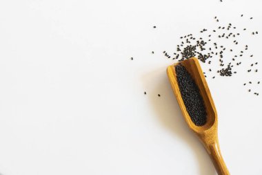 Tahta kepçe beyaz arka planda tatlı fesleğen tohumları. İzole et. Süper yiyecek ve sağlık hakkında metin ve tasarım için kopyalama alanı ile yatay