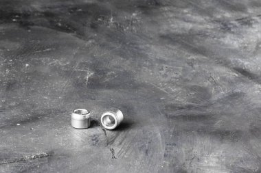 Siyah karatahta kırsal yüzeyinin arka planındaki dikdörtgen yatay çekimin sol tarafında iki metal gri nehir cevizi ve cıvata. kopyalama alanı ile