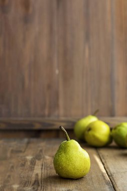 Arkaplanda çözünmüş armutlar olan taze, olgun, organik, kahverengi bir armut. Seçici odaklanma. Kopyalama alanı ile dikey. Tarım, meyve ve sağlıklı gıda tasarımı için.