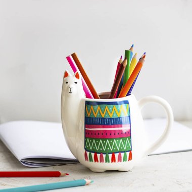 Beyaz Lama kupası renkli kalemler ve açık gri arkaplan üzerine taklit albüm, metin veya tasarım için metin alanı olan kare. Okul ve ofis için moda hayvan aksesuarları