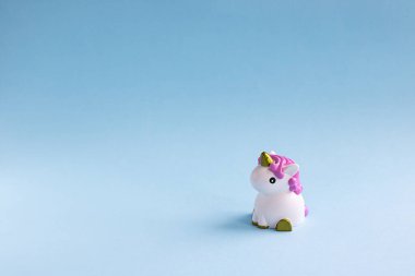 Açık mavi pastel arka planda şirin beyaz tek boynuzlu at. Bebek partisi, kız doğum günü konsepti. Kopyalama alanı ile yatay