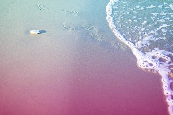 Отпечатки ног парня на песке на пляже и густая пенная волна. Один белый камень на гладкой линии костюма. Горизонтальный с голубым и фиолетовым дуотоном. Средиземное море, Кипр — стоковое фото