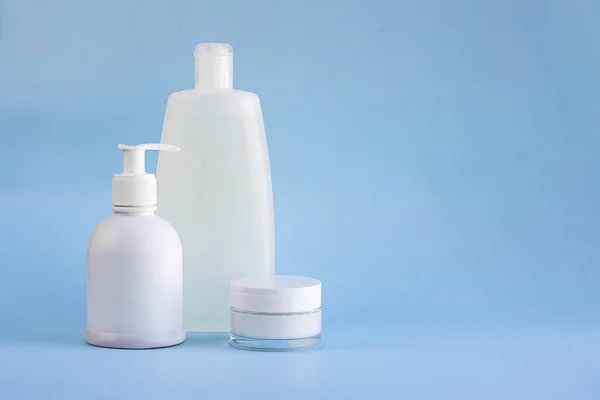 Şampuan veya duş jeli, şeker ve krem için cam küçük tüp için üç beyaz plastik maket şişesi açık mavi arka planda fotokopi alanı ile