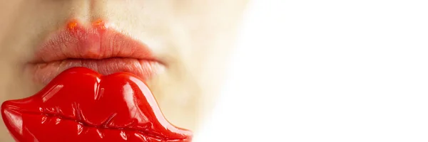 Часть молодой женщины лицо с красными пузырьками вирусного герпеса на губах, что она пытается скрыть с игрушечными губами для фото на Patry. Лекарство, лечение. Длинный горизонтальный баннер с копировальным пространством — стоковое фото