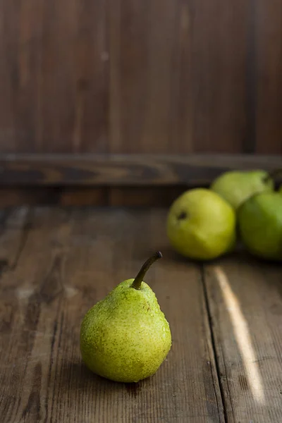 One fresh ripe organic yellow pear on rustic wooden brown table with defocused pears on background. Selective focus. Vertical with copy space. For design about agricilture, fruit and healthy food — Stock Photo, Image