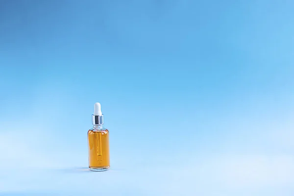 Mavi arka planda yağlı portakal şişesi. İnce vücut ve güneş kremi hakkında güzellik ve kozmetik konsepti, sağlık derisi, saç koruması, ultraviyole filtre. Kopyalama alanı ile yatay