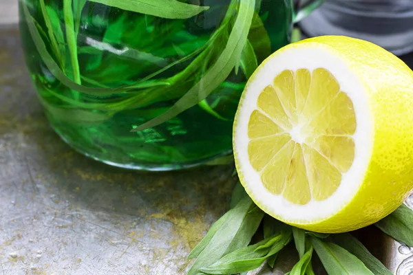 Eine halbe frische gelbe Zitrone mit defokussiertem grünen Getränk mit Estragon auf dem Hintergrund. Zutat für Schaumgetränk, Alkoholgetränk. horizontal, Kopierraum — Stockfoto