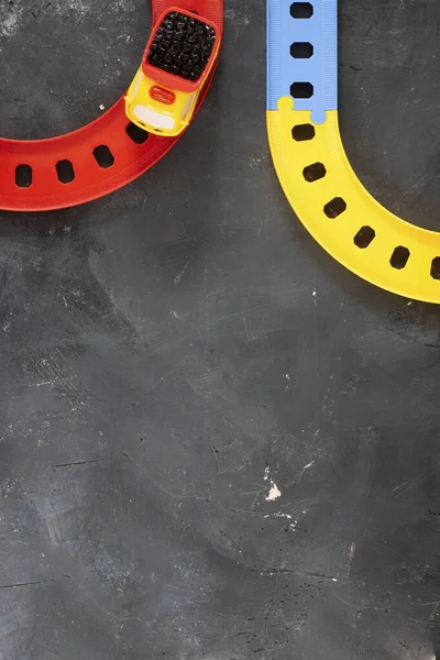 Plastik-Spielzeug-LKW auf gebogener Straße auf schwarzem Tafelhintergrund mit Kopierraum. Ansicht von oben. Kreatives Konzept für das Transportsystem, Dinge für Kinder spielen, Bildung und Programme für Unternehmen. — Stockfoto