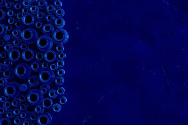 Farklı boyutlarda perçin perçin fındıkları, paslanmaz çelik mandrel, çekimin sol ucunda siyah tebeşir kaplı tahta yüzeyi. Klasik, mavi monokrom, trend 2020. Fasteners, vidalar ve detaylar.