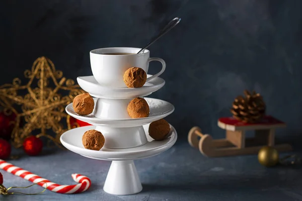 Concept créatif avec plats blancs Pyramide en forme d'arbre de Noël avec tasse de thé sur le dessus décoré de truffes au chocolat sucré sur fond sombre. Papier peint, carte postale à propos de Noël, Nouvel An. Horizontal — Photo