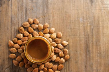 Kayısı çekirdekleri bir avuç dolusu ve ahşap arka planda fındık ezmeli cam kavanoz. Fotokopi alanı ile yemek. Ürün kardiyo vasküler sistem için iyidir, parazitler için tedavi, vitaminlerle doludur. Üst görünüm