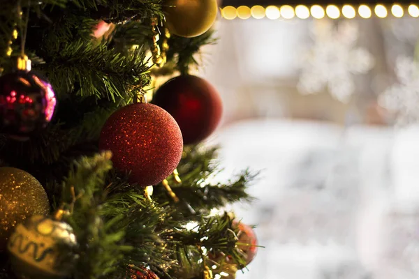 Süslemeli yapay noel ağacı. Arka planda kırmızı toplar var. Kar taneleri ve bokeh ışıkları var. Tatillerde ve partilerde otel ve restoran rezervasyonu. Kopyalama alanı ile yatay