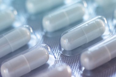 Yakın plan haplar. Çapraz oval uzun şekil çaresi sırası. Yatay olarak. İnsan vücudunu desteklemek için ilaç, sağlık, vitamin, bağışıklık sistemi virüsleri ve enfeksiyonlar hakkında geçmiş ya da dokular. Mavi ton