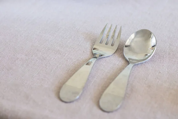 Metal bebek kaşığı ve çatal. Masanın üzerinde, tasarım için fotokopi alanı ile kaplı kumaş var. Çocuklar için plastik tabak kullanmayı reddetmek, sıfır atık. Yeni yürümeye başlayan çocuk için eko pişirme. Sorumluluk sahibi ebeveynler. Çocuk için sofra takımı
