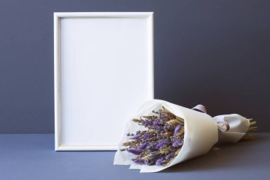 Kurumuş çiçeklerin bileşimi ve gri arkaplan fotokopi alanı üzerinde bir fotoğraf çerçevesi