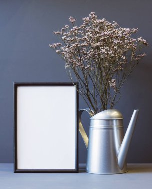fotoğraf çerçevesi ve kurumuş çiçeklerin kompozisyonu bir sulama kutusunda gri bir arkaplanda fotokopi alanı ile