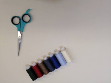 beyaz arkaplanda makas dikmek için renkli iplik makaraları