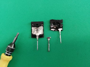 Yeşil arka planda tornavidayla eski bozuk bipolar transistör.