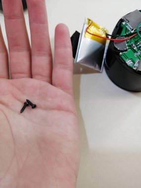 Aydınlatma arka planında tamir için sökülmüş müzik sütununun avuç içine küçük vida