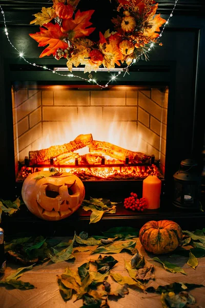 Creepy halloween pumpkin near a fireplace. Fire and dry leaves on the background. Jack of the Lantern, copyspace. Shoot in the dark.