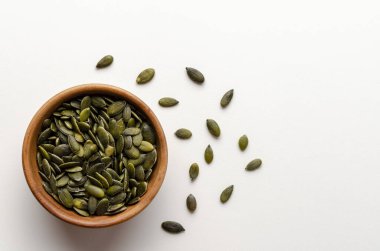 Beyaz arka planda tahta bir kasede kabak tohumları