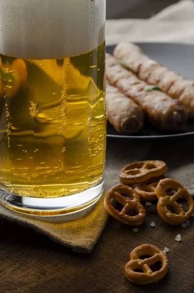 Salsichas grelhadas com pretzels e canecas de cerveja — Fotografia de Stock